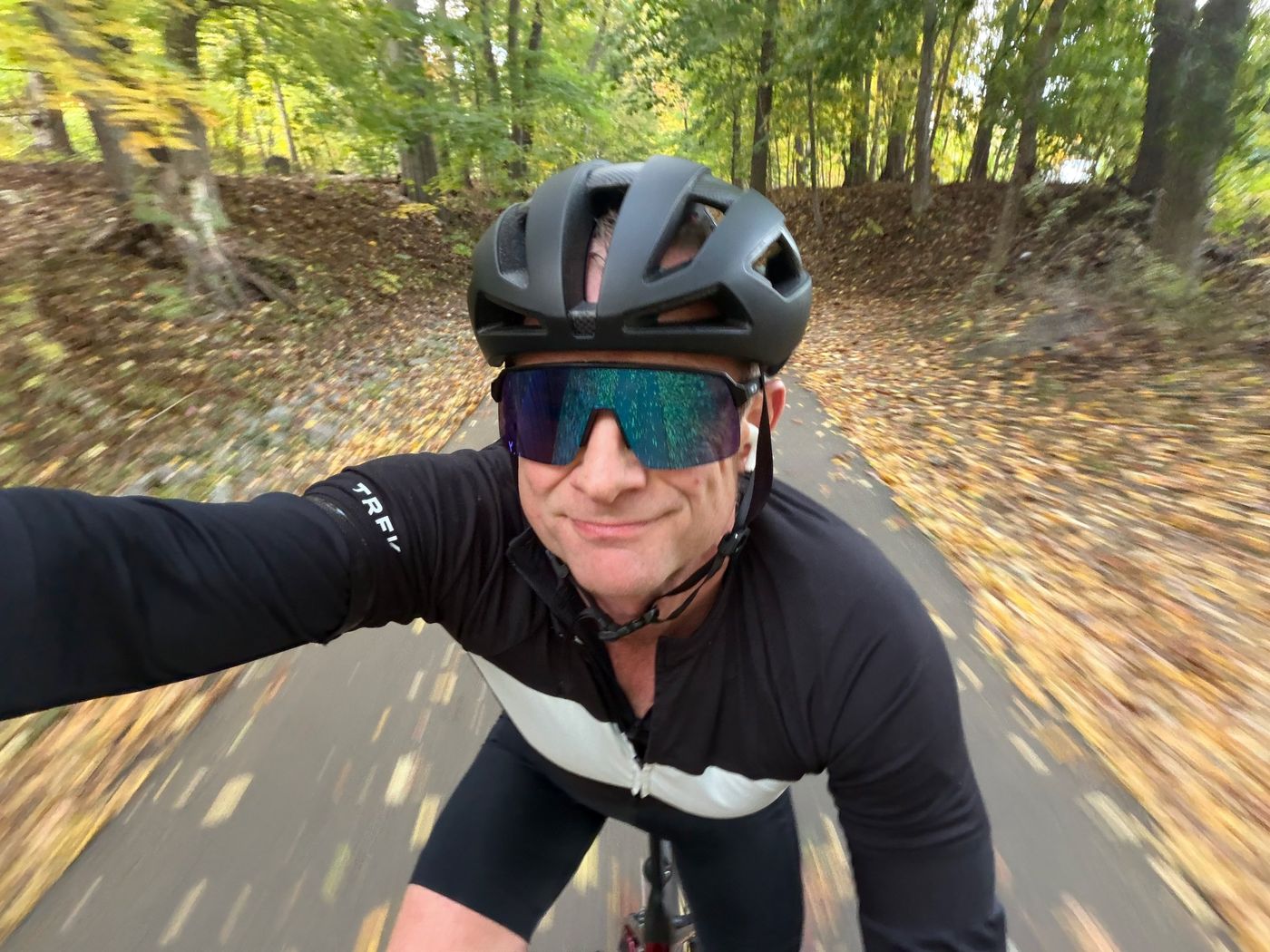 Adam road cycling on a leaf-covered trail through autumn woods